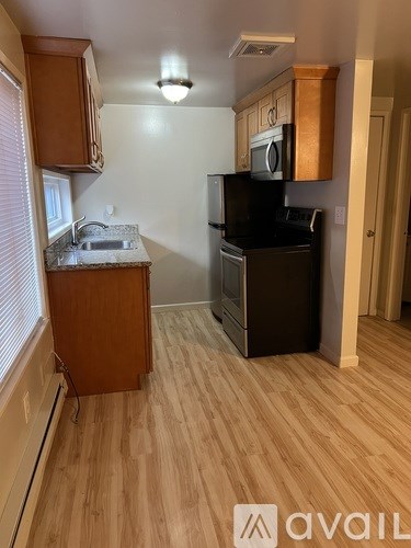 A kitchen with wooden cabinets and a black fridge.