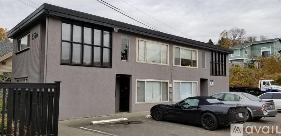 A grey house with a black car parked in front.