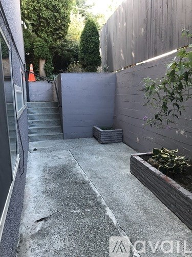 A concrete staircase with a grey wall on the side and a planter box on the ground.