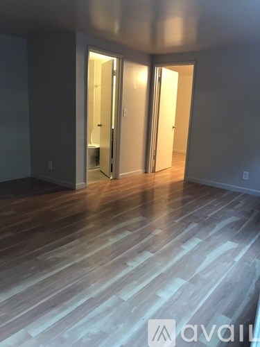 A room with wooden floors and two open doors.