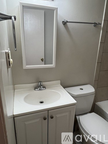 A white bathroom with a toilet, sink, and medicine cabinet.