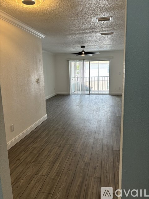 A room with a ceiling fan and sliding glass doors.