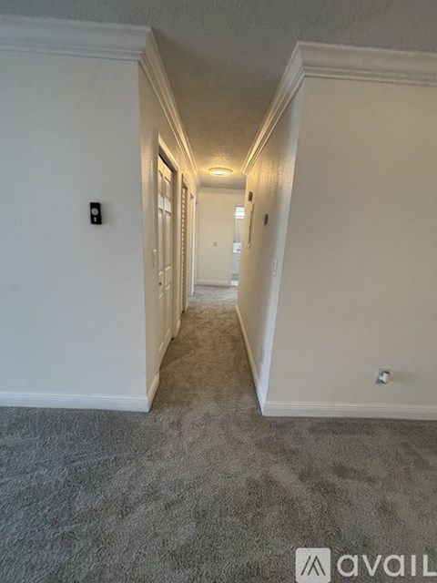 A long hallway with white walls and wood flooring.
