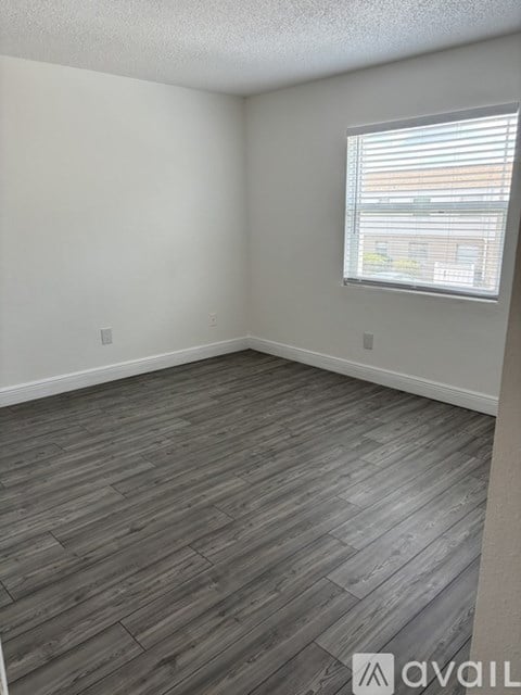 A room with wooden flooring and a window with blinds.