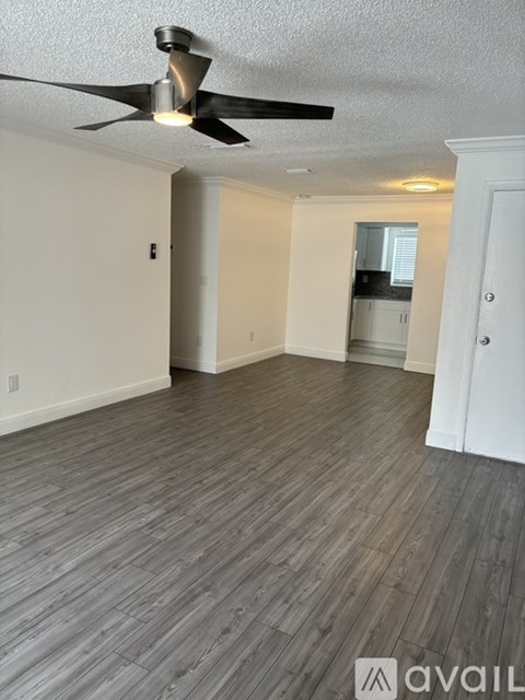 A room with a ceiling fan and wooden flooring.