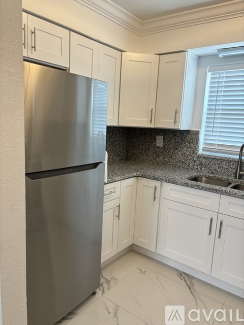 A kitchen with a stainless steel refrigerator and white cabinets.
