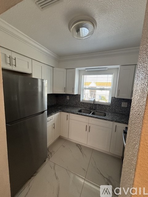 A kitchen with black appliances and white cabinets.