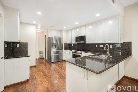 A kitchen with white cabinets and a black countertop.