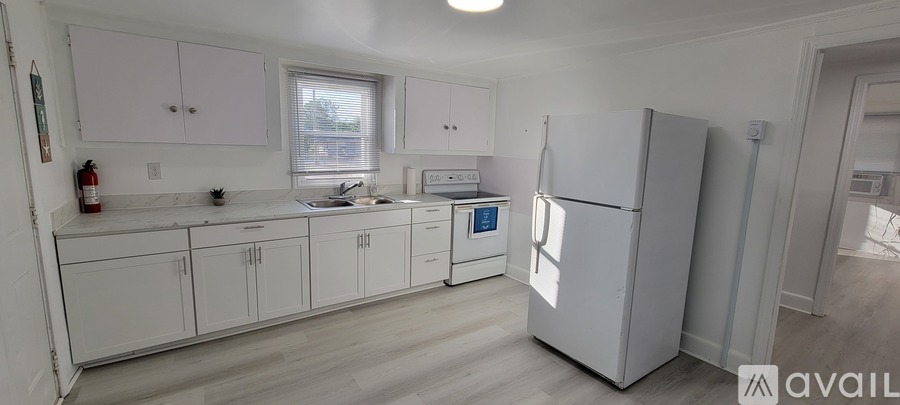 A kitchen with white cabinets and a white fridge.