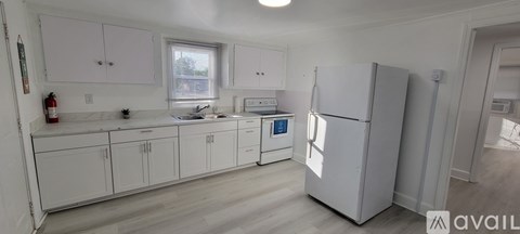 A kitchen with white cabinets and a white fridge.