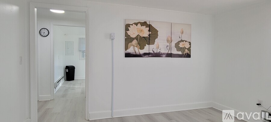 A room with a clock on the wall and a painting of flowers.