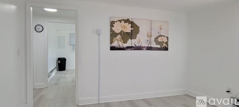 A room with a clock on the wall and a painting of flowers.