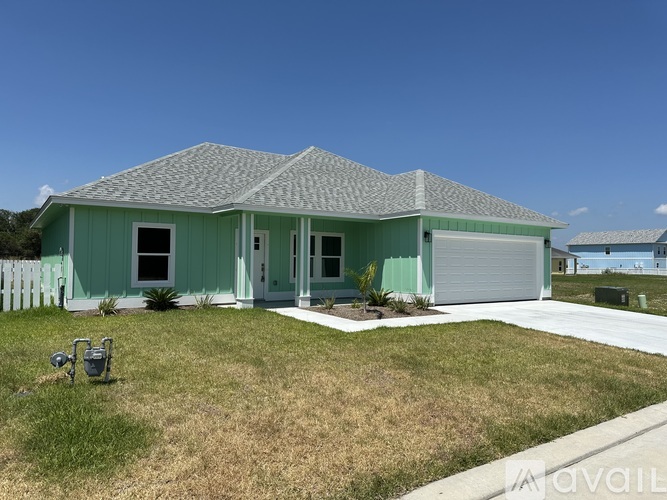 A house with a green exterior and a grey roof is for sale.