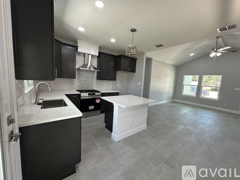 A modern kitchen with black cabinets and a white island.