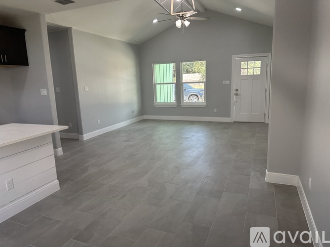 A spacious room with a ceiling fan and grey flooring.