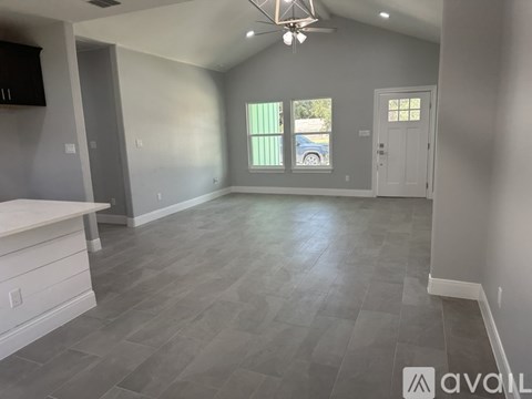 A spacious room with a ceiling fan and grey flooring.