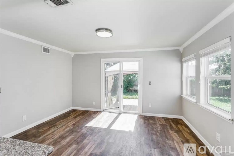A room with a wooden floor and a sliding glass door leading outside.