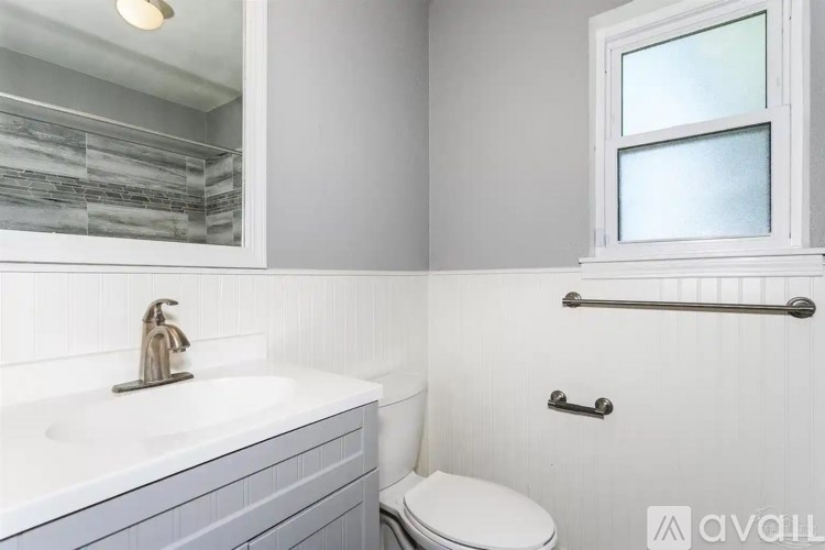 A bathroom with a toilet, sink, and a window.
