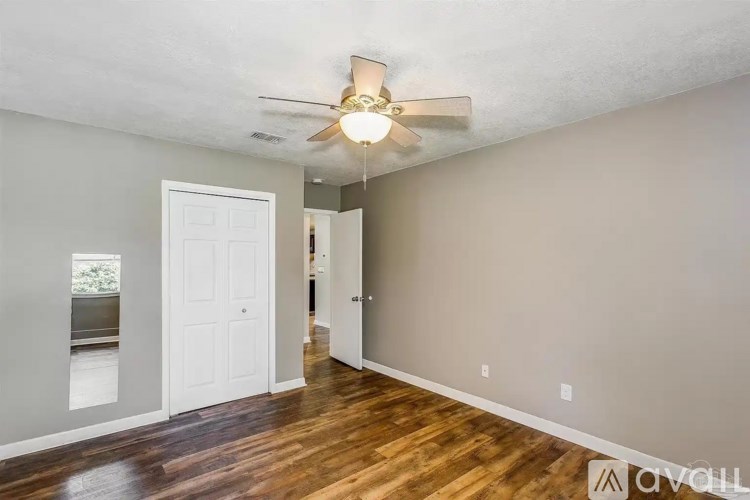 A room with a ceiling fan and wooden floors.