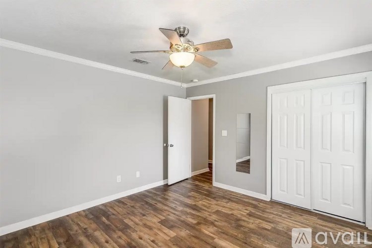 A room with a ceiling fan and wooden flooring.