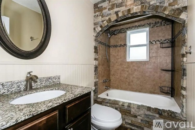 A bathroom with a stone wall and a tub.