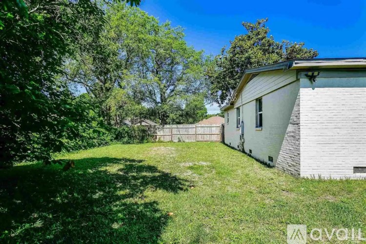 A house with a yard and trees in the background.