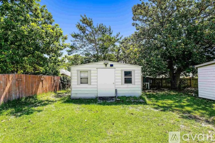 A white house with a brown fence and trees in the background.