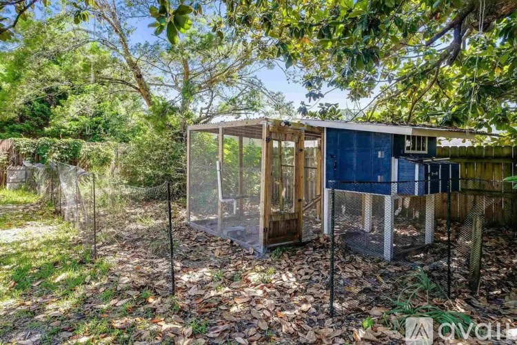 A small blue building with a glass door is surrounded by a wire fence.