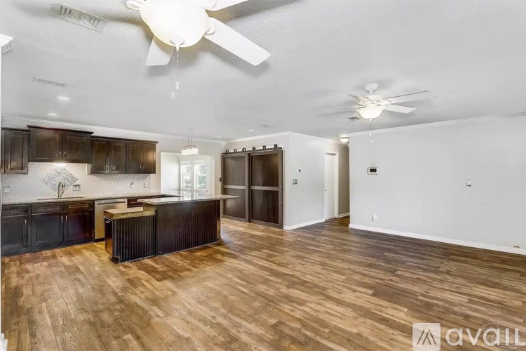 A spacious room with wooden flooring and a ceiling fan.