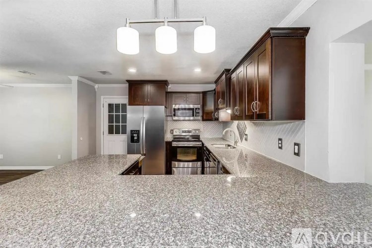 A kitchen with a granite countertop and wooden cabinets.