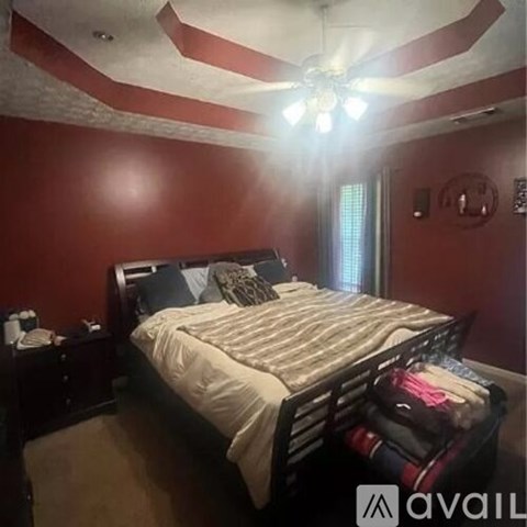 A bedroom with a bed, nightstand, and a ceiling fan.