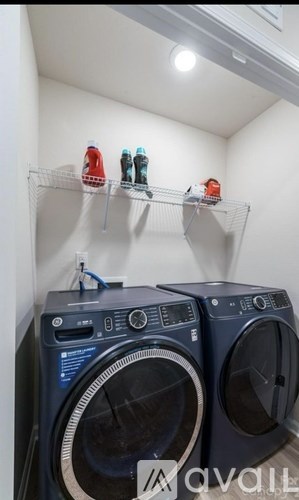 A wall-mounted shelf holds three bottles above a pair of washing machines.