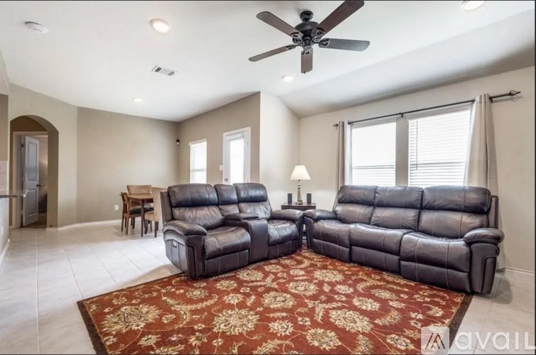 A living room with a rug and two leather sofas.