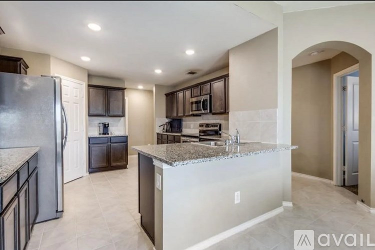A kitchen with a refrigerator, sink, and cabinets.