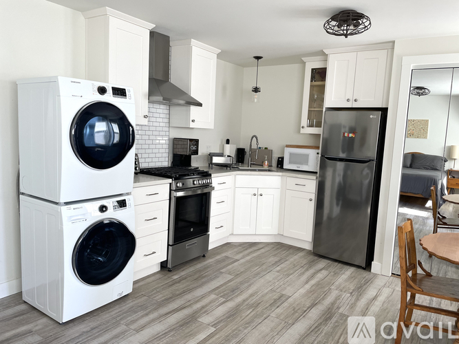 A modern kitchen with a white washing machine and a black fridge.