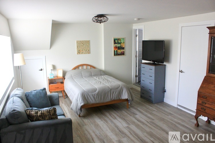 A bedroom with a bed, dresser, and couch.