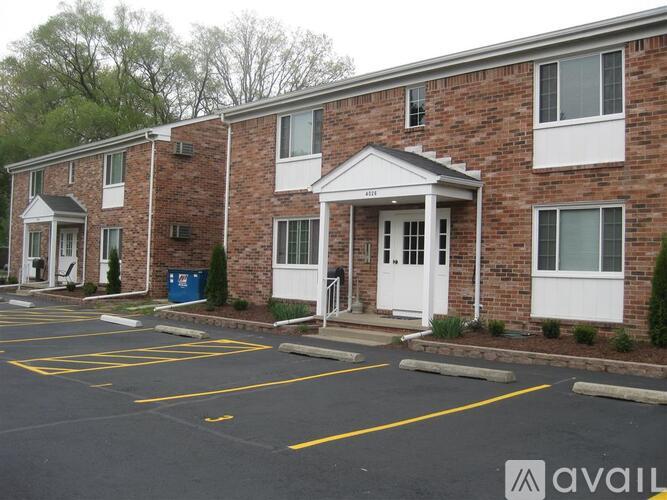 A brick apartment building with a parking lot in front.