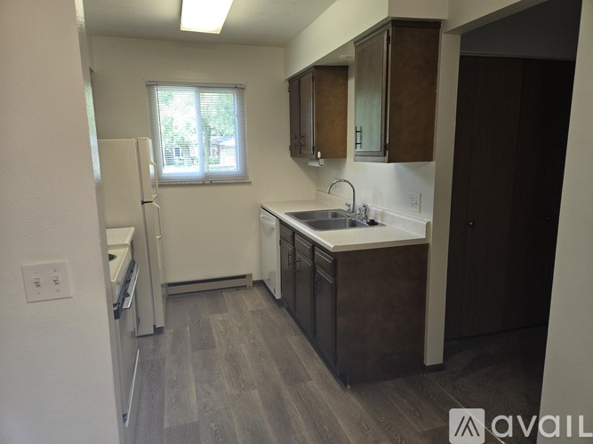 A kitchen with a white fridge, brown cabinets, and a window.