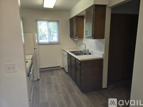 A kitchen with a white fridge, brown cabinets, and a window.