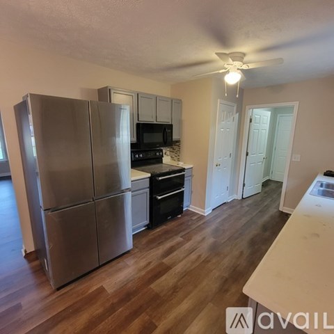 A kitchen with a refrigerator, microwave, oven, and sink.