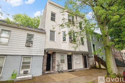 A two-story building with a front yard and a tree.