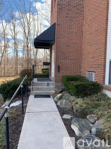 A brick building with a black awning and a stone pathway leading to the entrance.