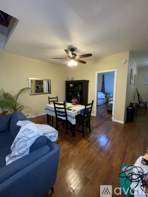 A living room with a blue couch and a dining table with chairs.