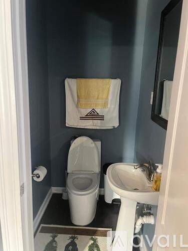A bathroom with a toilet, sink, and a towel hanging on the wall.