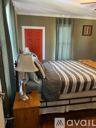 A bedroom with a bed, nightstand, and lamp.