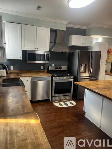 A kitchen with a wooden counter top and stainless steel appliances.