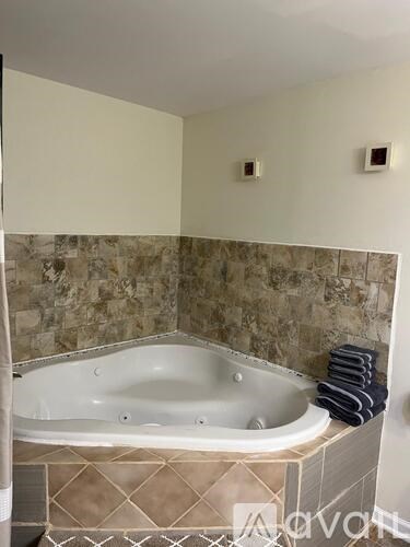 A bathtub sits in a bathroom with a tiled wall.