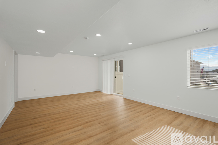 A spacious room with wooden flooring and white walls.