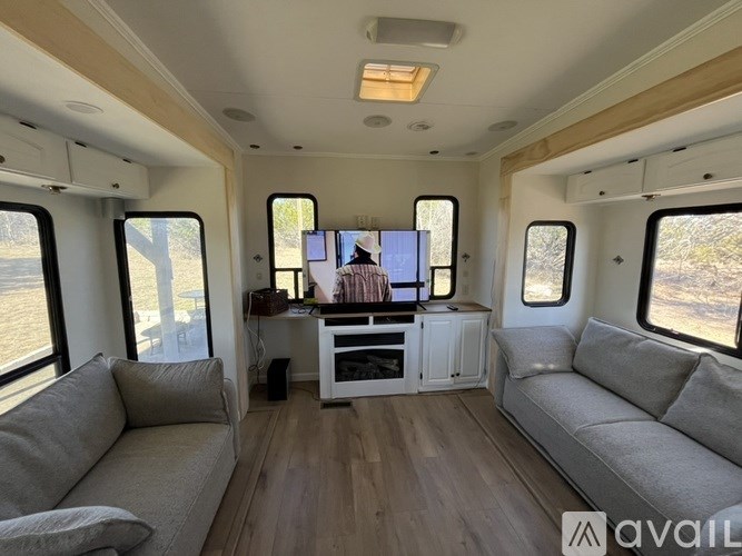 The image shows the interior of a vehicle with a couch, a table, and a TV.