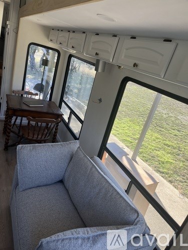 A grey couch is in front of a window with a view of a lawn.